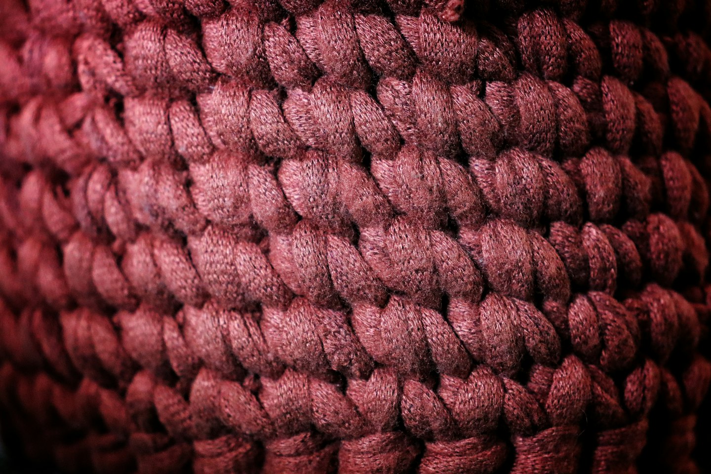 Jemná textúra hrubého, červenohnedého pleteného priadzového materiálu.